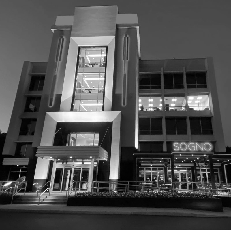A modern, three-story office building at night with illuminated windows and a sign reading “SOGNO” above an entrance, showcasing the innovative MEP/FP designs by Engineered Systems Inc.